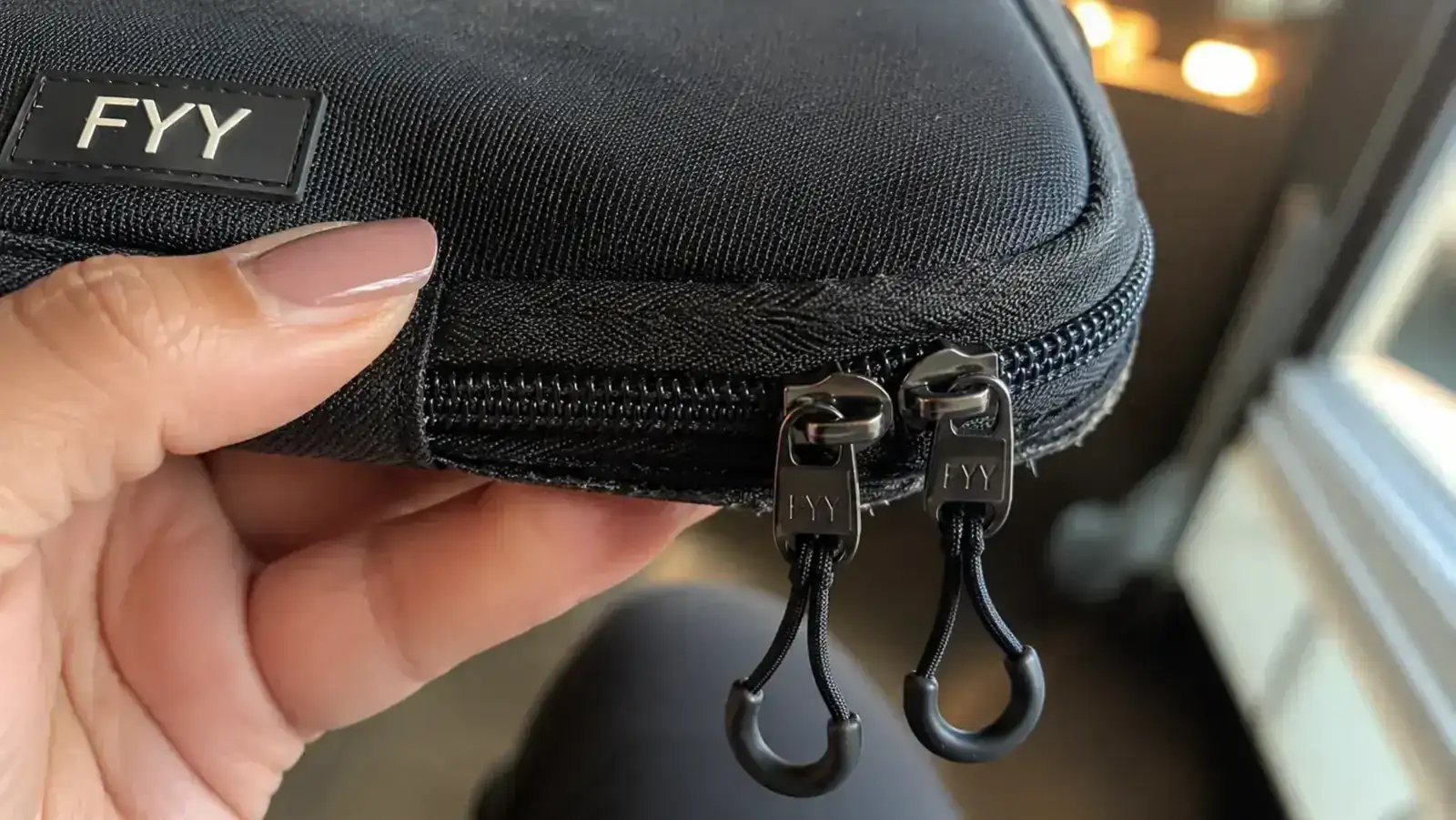 Close-up of the FYY cable organizer zipper and outer pocket showing wear after heavy travel use