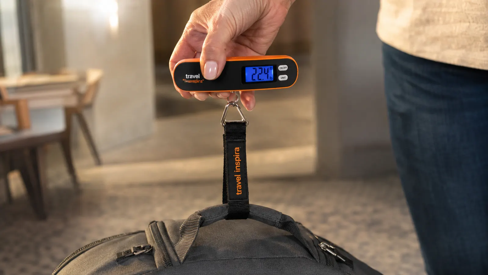 Hand holding the travel inspira luggage scale strap while weighing a carry-on bag